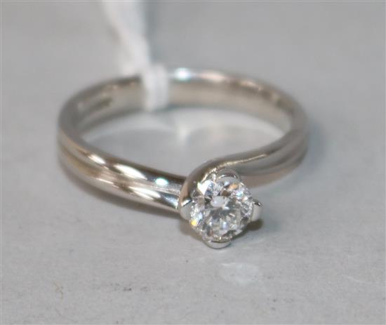 A modern 18ct white gold and twist claw set solitaire diamond ring, size M.